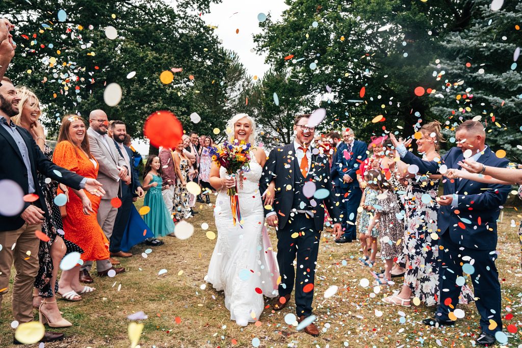 bride and groom have big, bold confetti thrown on them