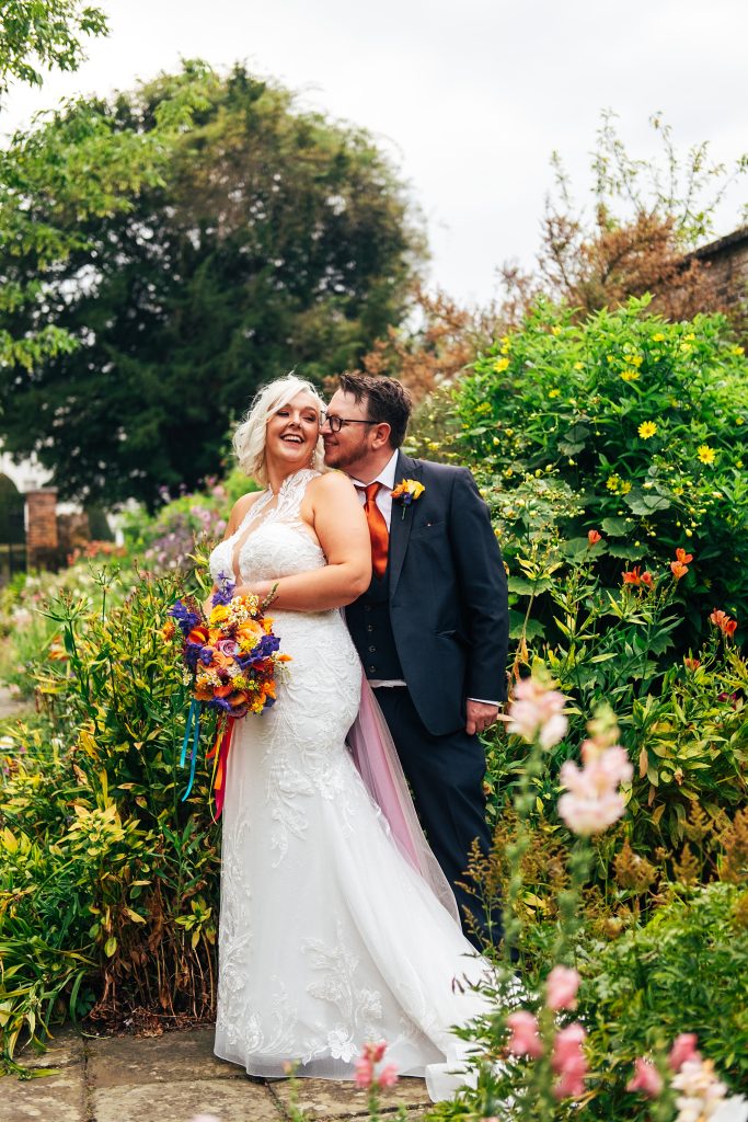 bride and groom stand in walled garden