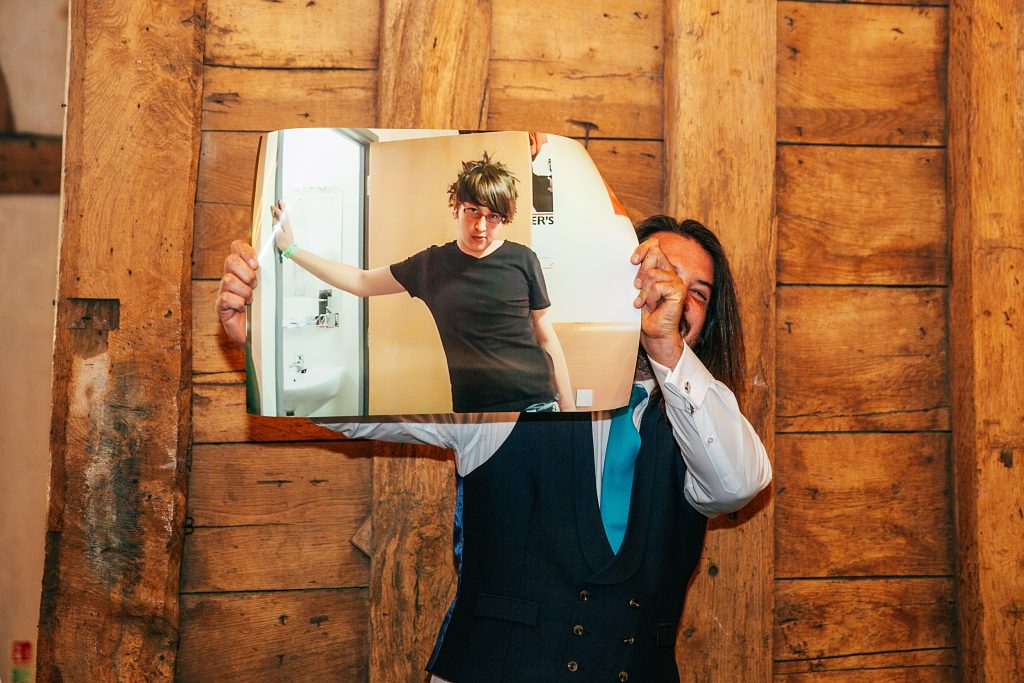 bedt man holds up large photo of groom