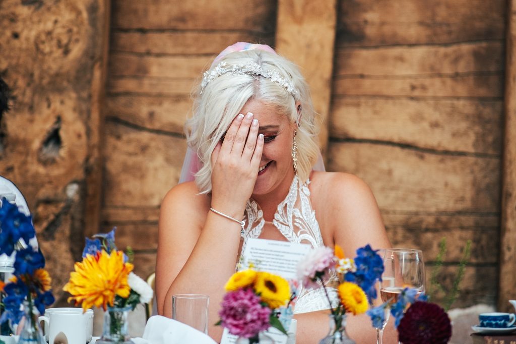 bride holds head in hands during speeches