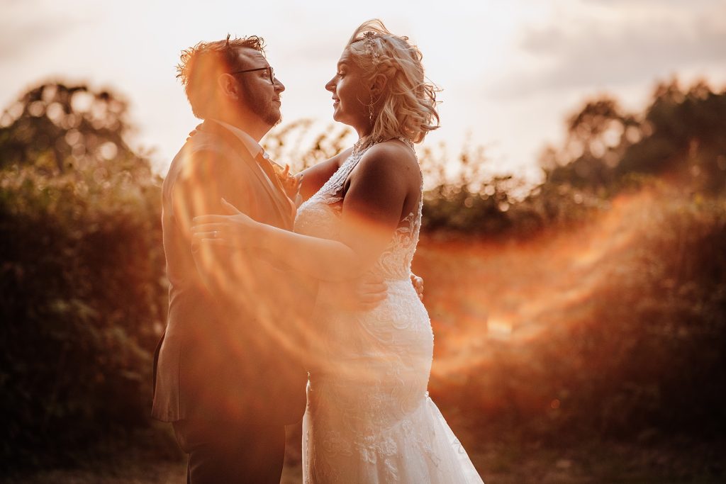 bride and groom at sunset with lens flare