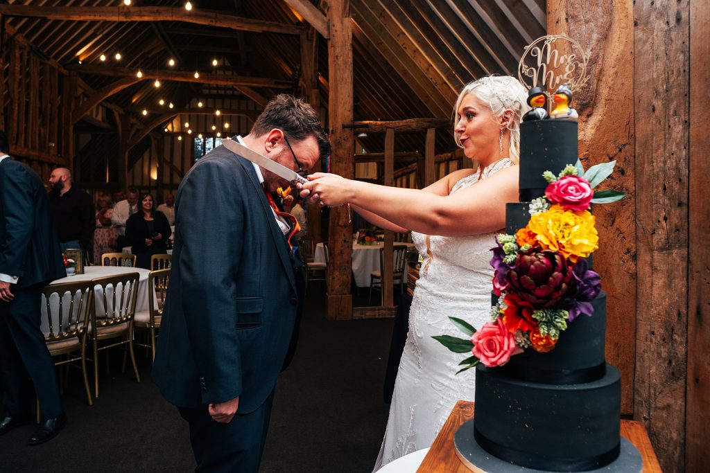 bride pretends to knight groom with cake knife