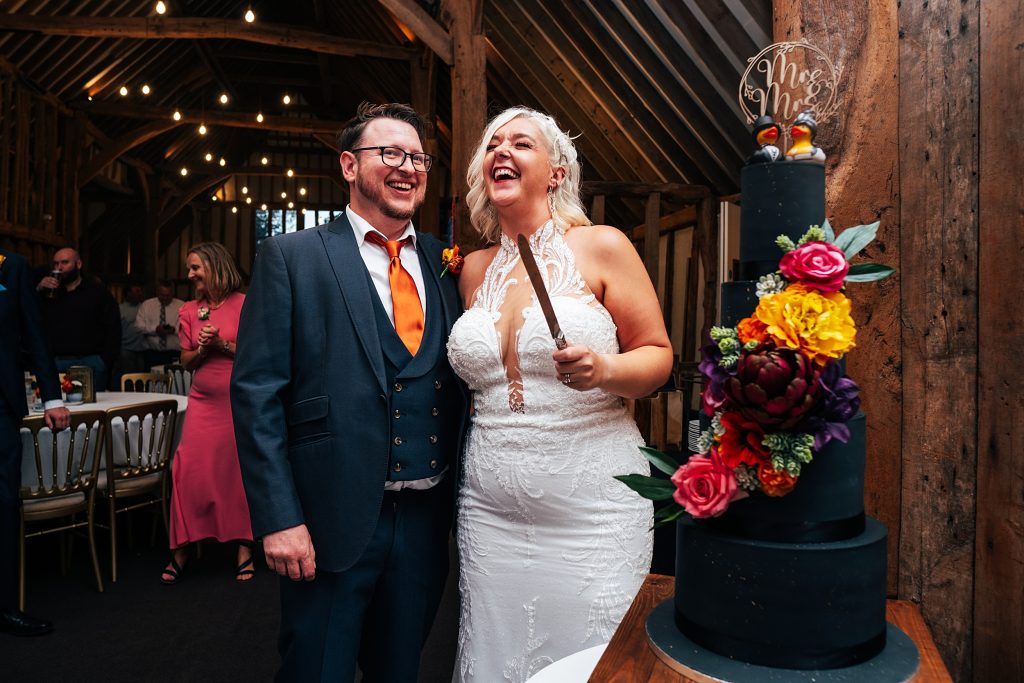 laughing bride and groom cut cake