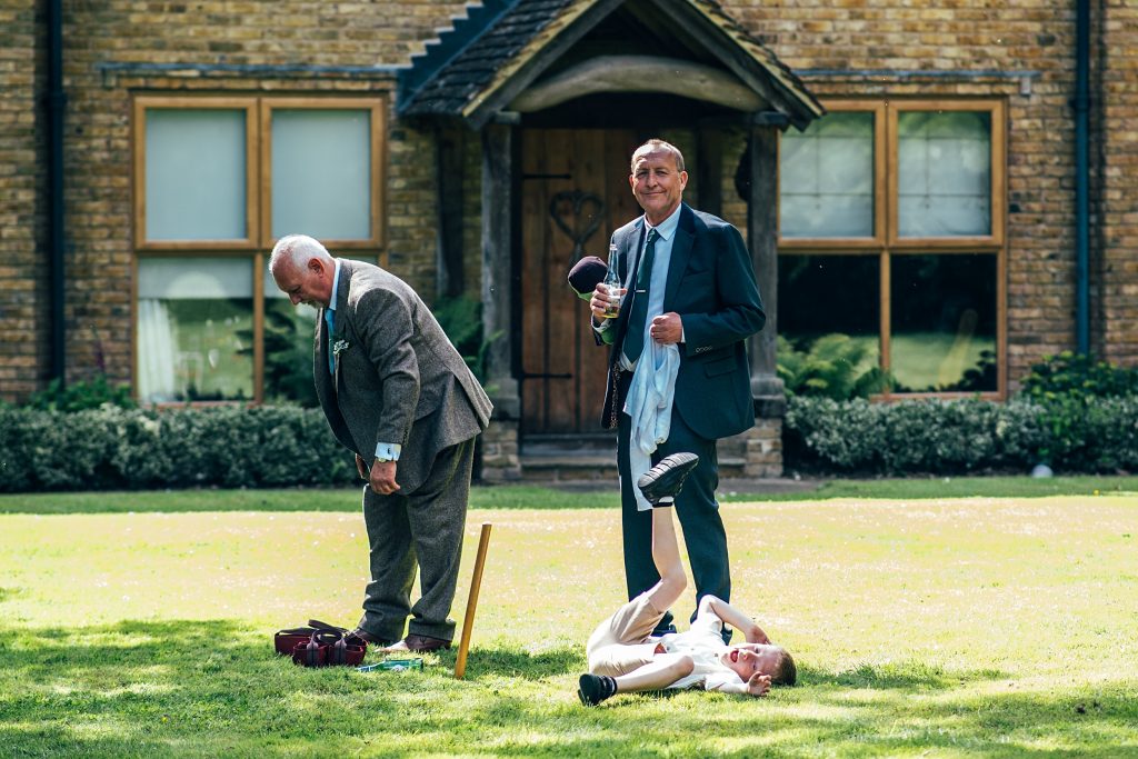 two men and a boy on the ground play cricket