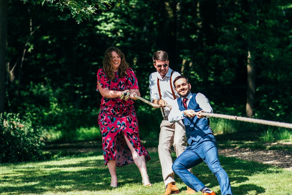 3 wedding guests play tug of war