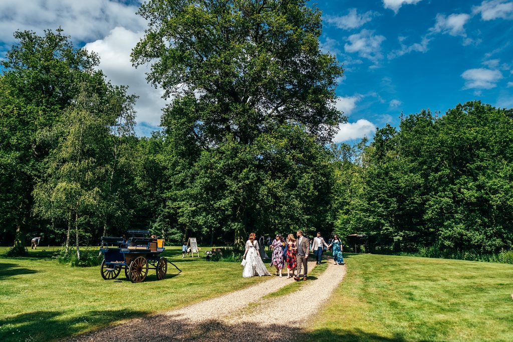 guests walk in woodland at wedding