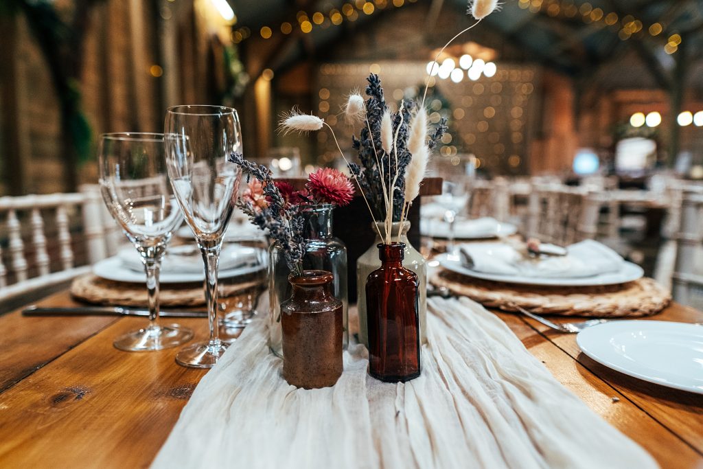 glass bottles with dried flowers on tables