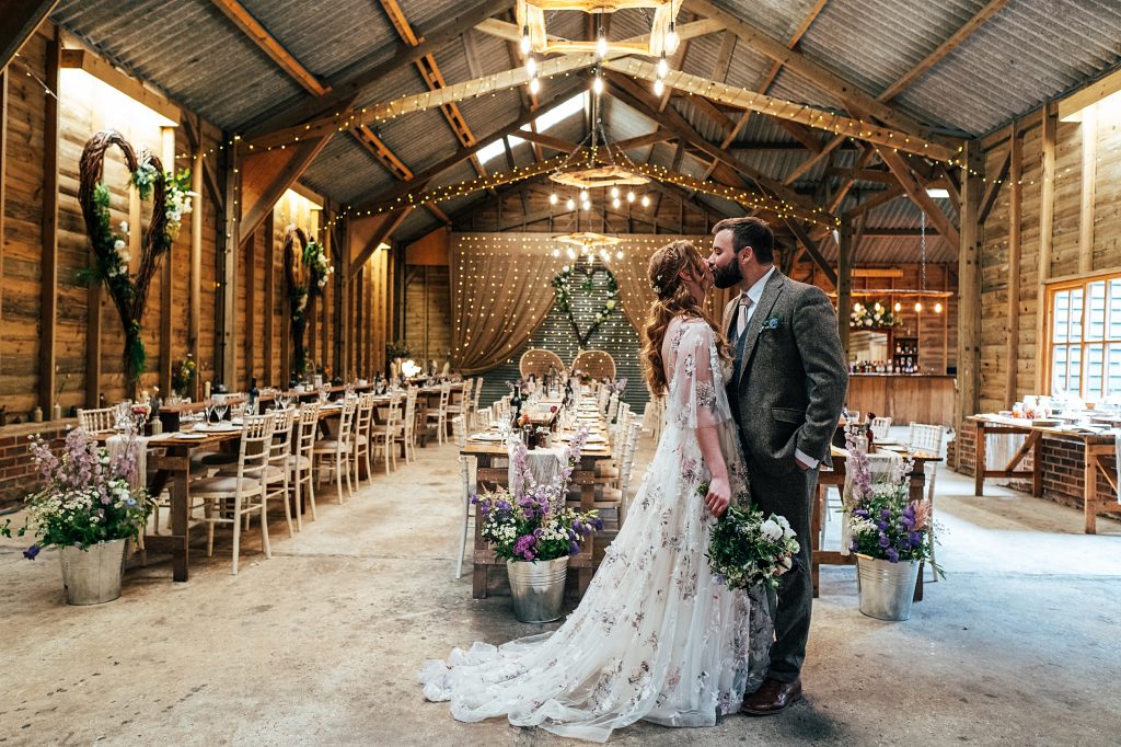 bride and groom kiss in wedding breakfast barn