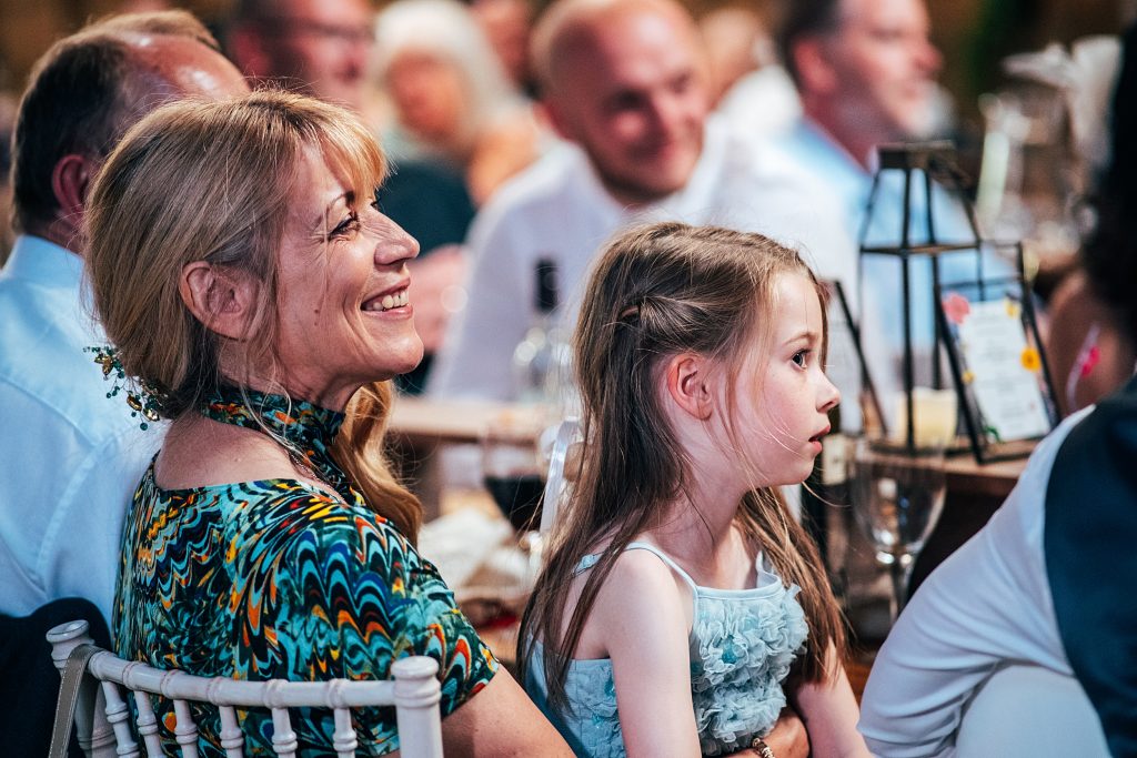 wedding guest laughs at speeches with little girl on her lap