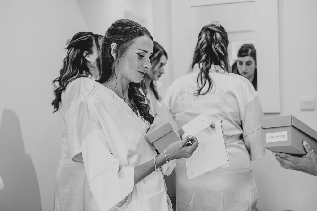 bridesmaid in dressing gown smiles at a gift she's opened