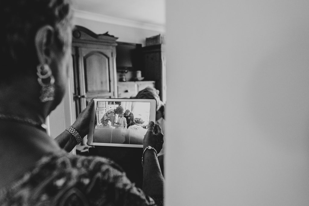 grandmother takes photo on iPad of little boy getting ready on wedding morning