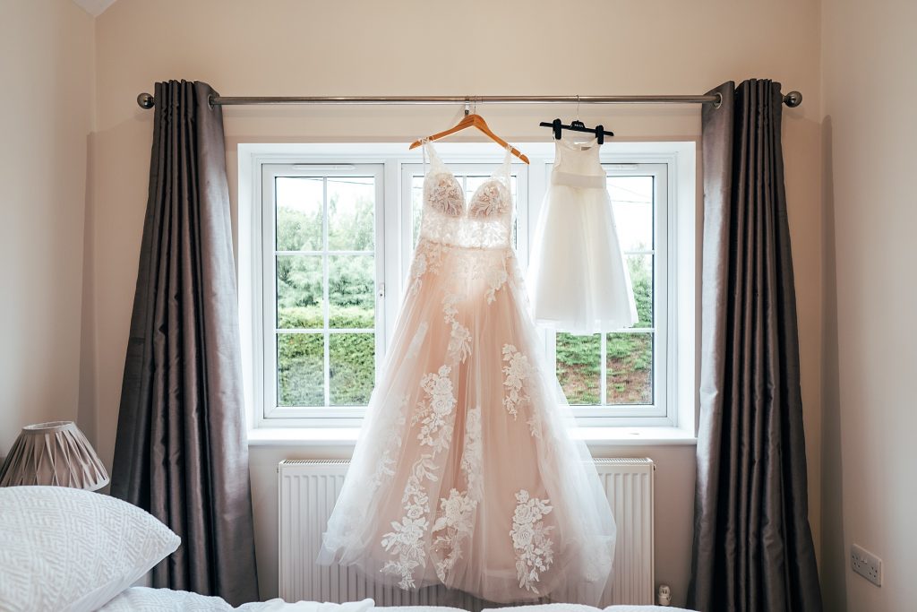 wedding dress and flower girl dress hang in window