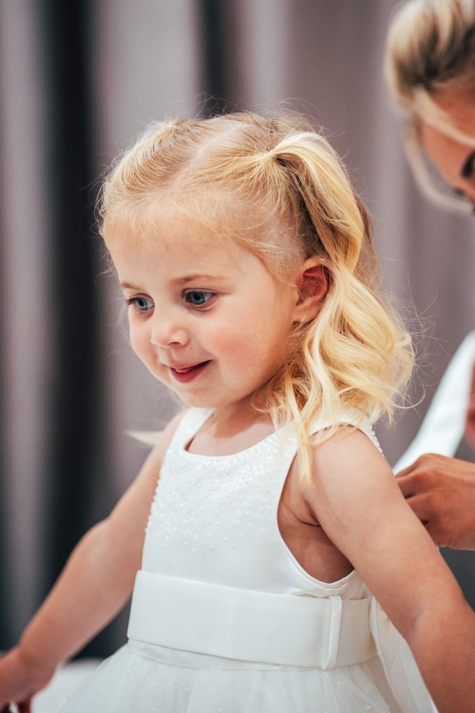 little girl has dress done up on wedding morning