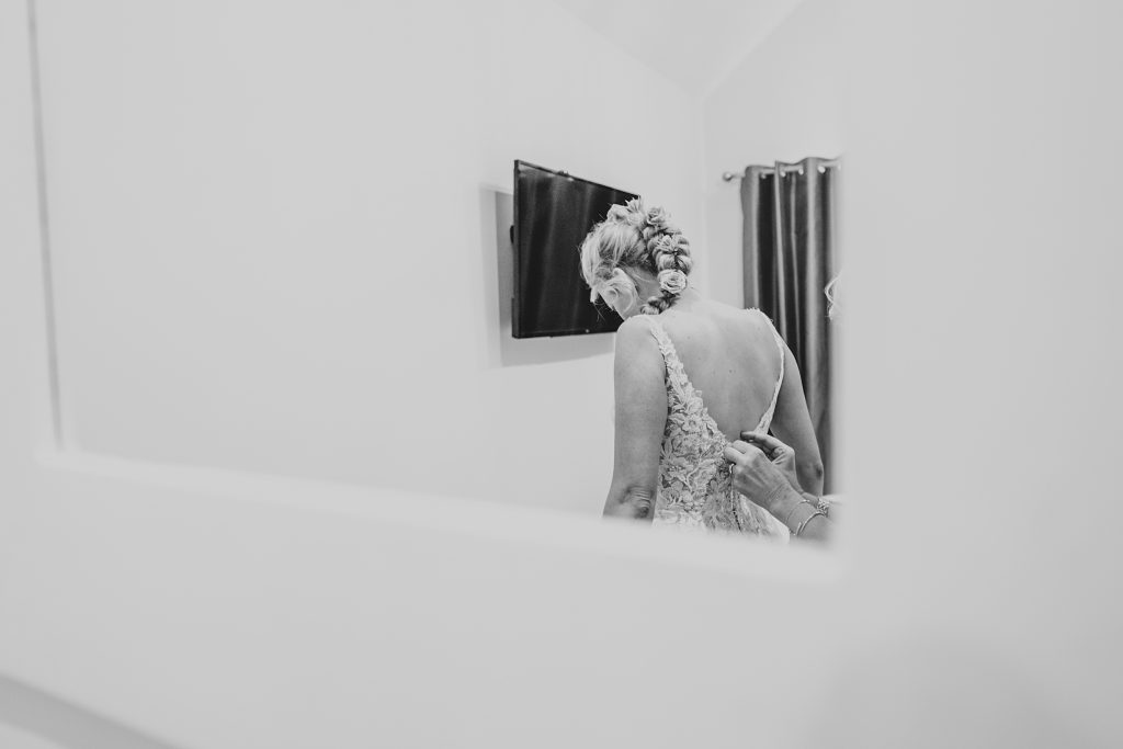 brides reflection in mirror as she has her dress done up