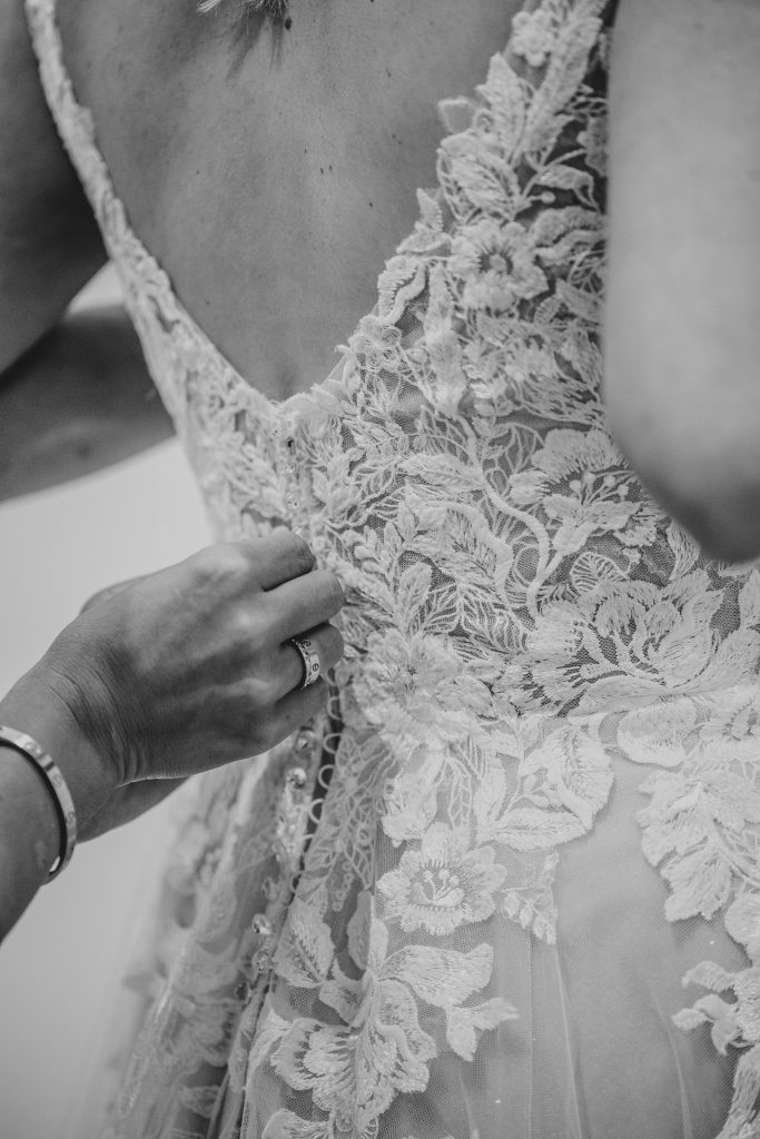 close up of buttons being done up on brides dress