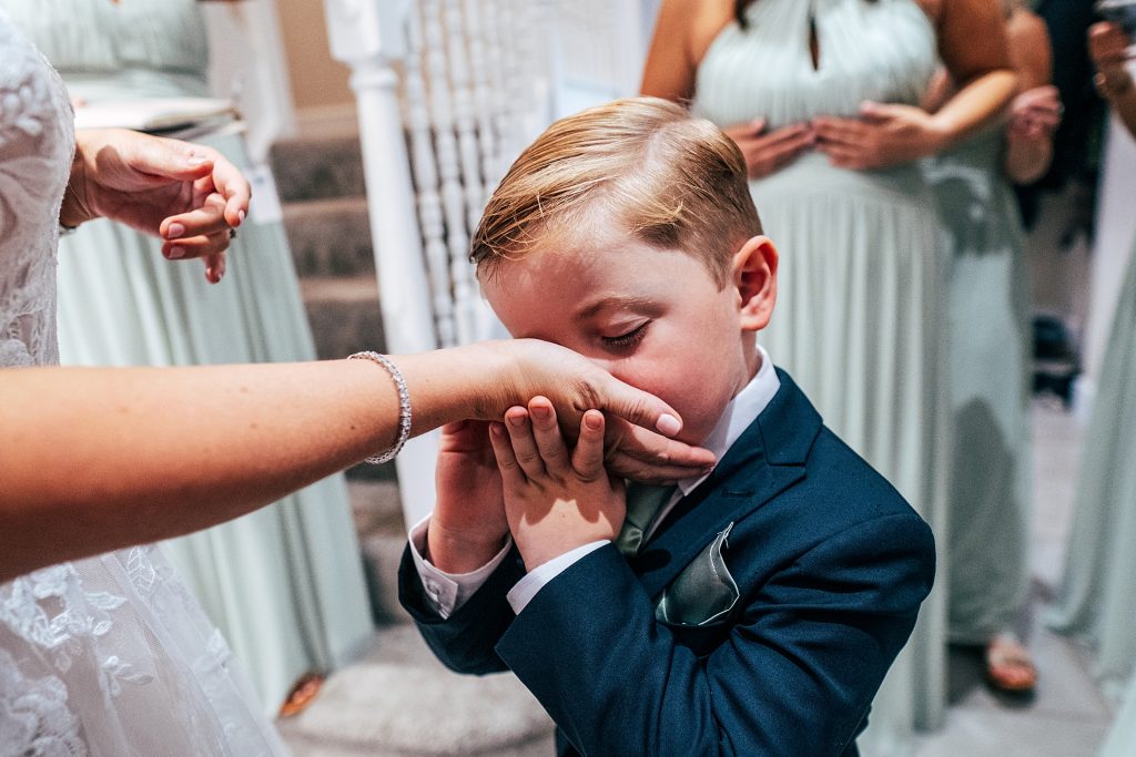 little boy in suit and tie kisses his mums hand