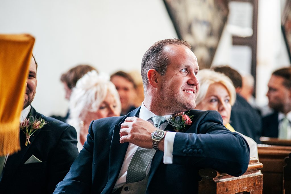 smiling groom waits for bride in church