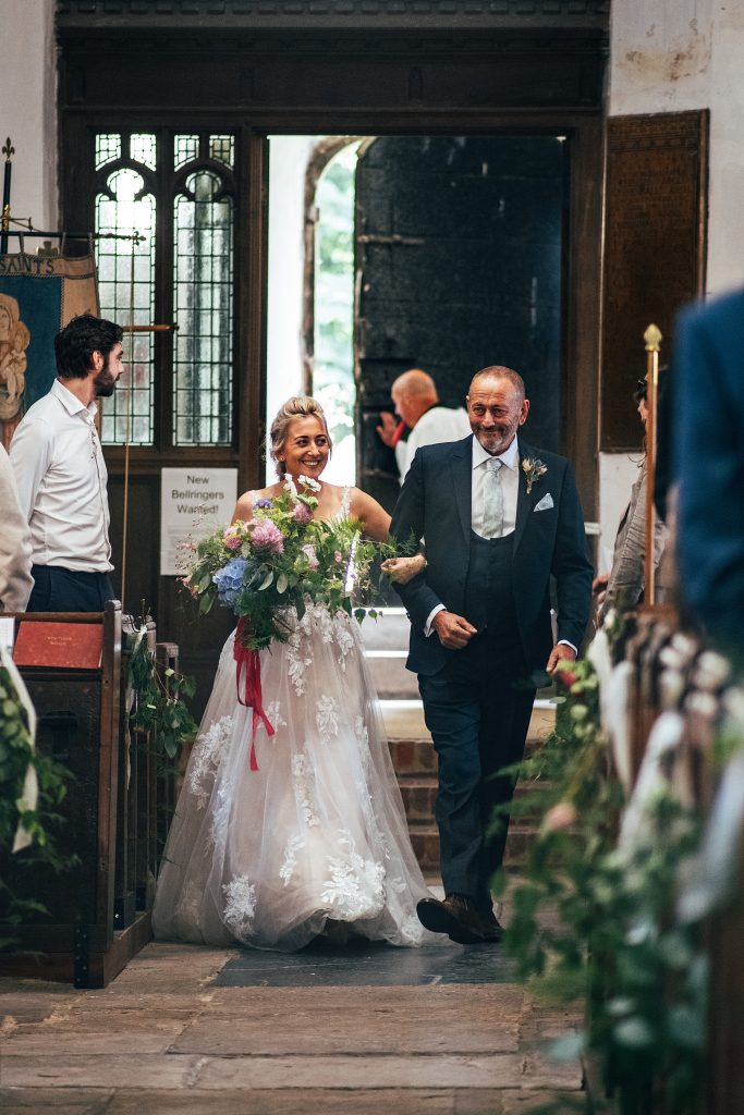 bride walks down aisle with dad in church
