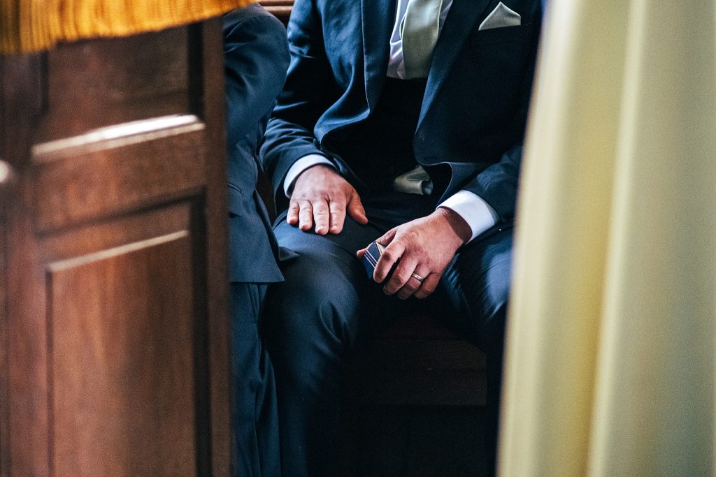 close up of best man holding rings in church