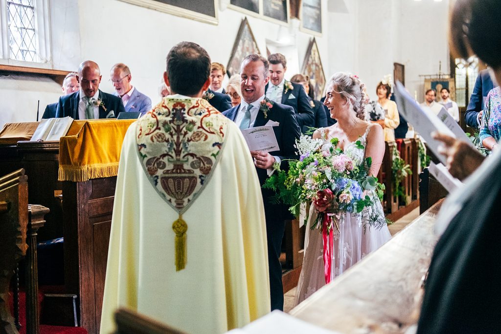 bride and groom laugh as they sing hymns in church