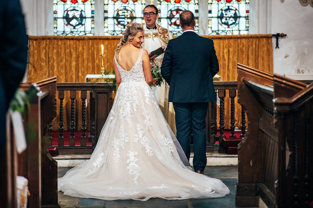 bride turns and smiles to guests behind her at church