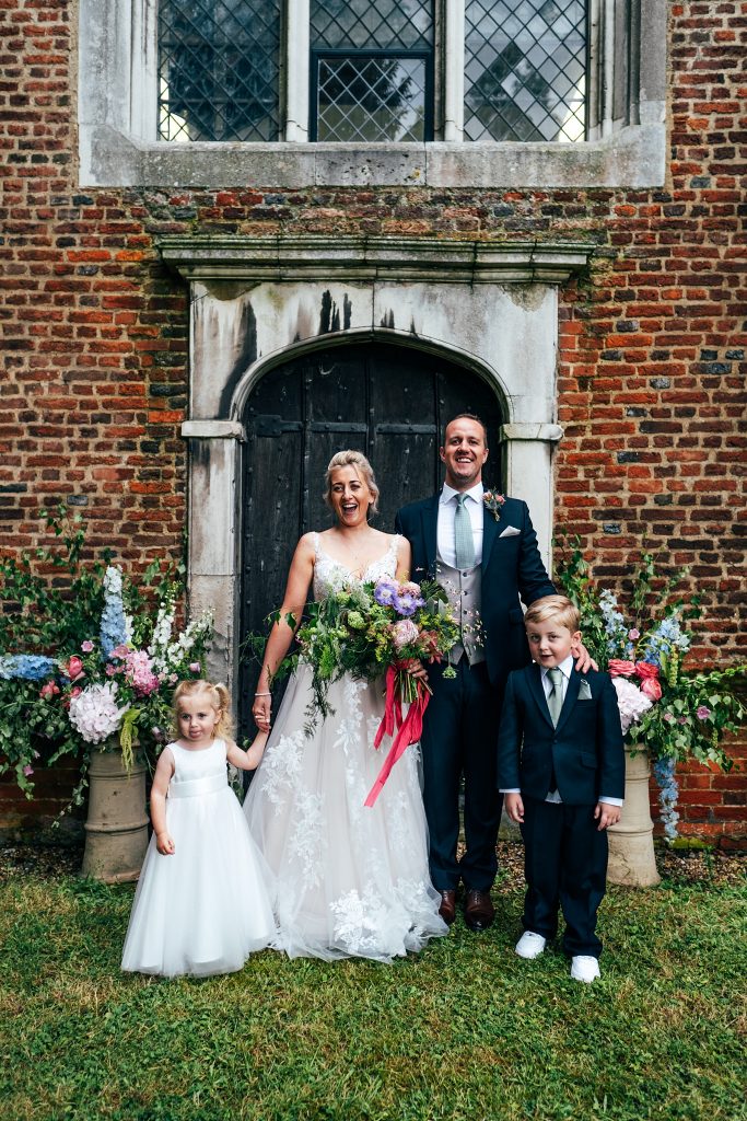 bride and groom with children in church doorway