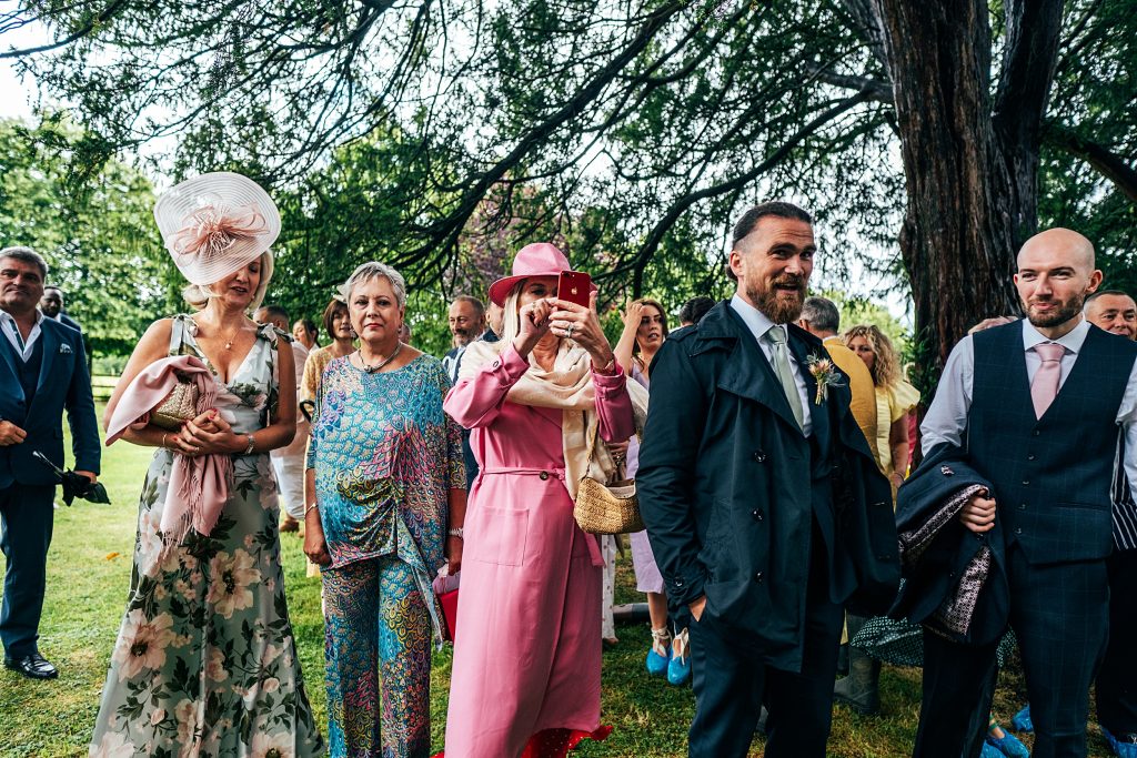 wedding guests take photos in churchyard