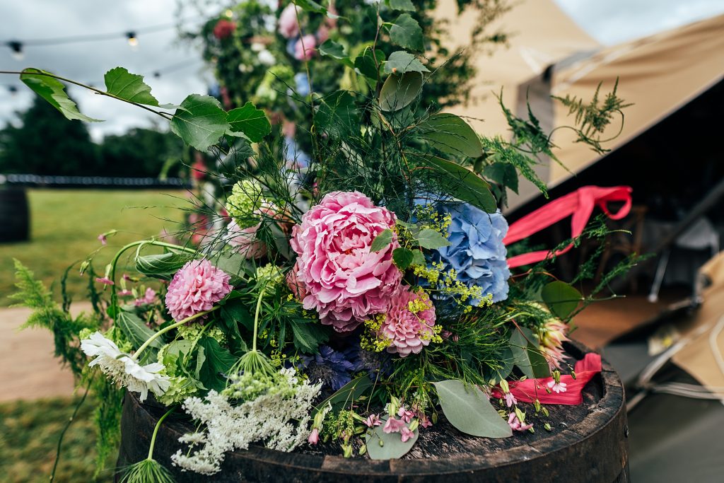 brides wild flower bouquet on barrel outside tipi