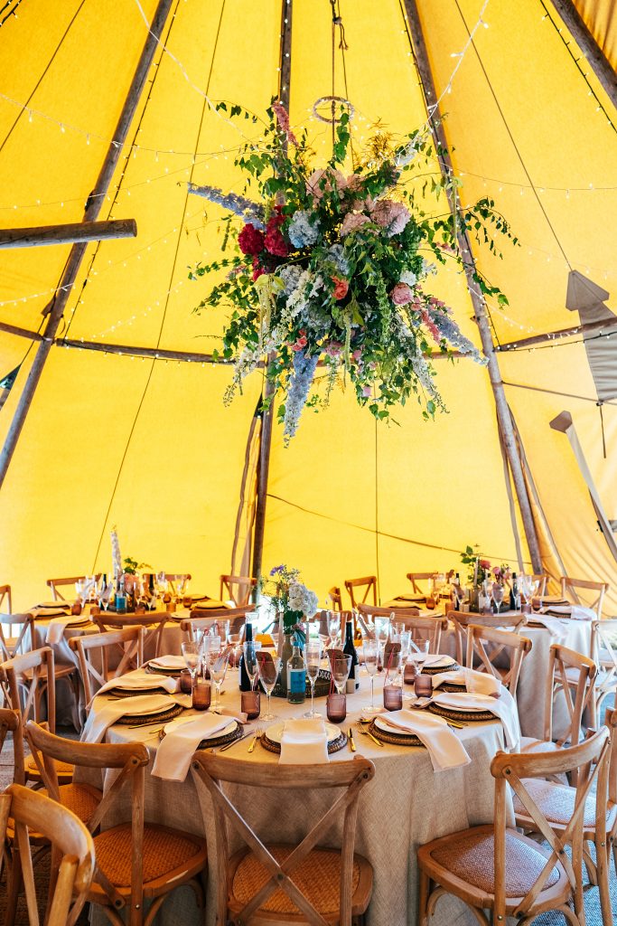 huge hanging floral bomb in ceiling of tipi above table