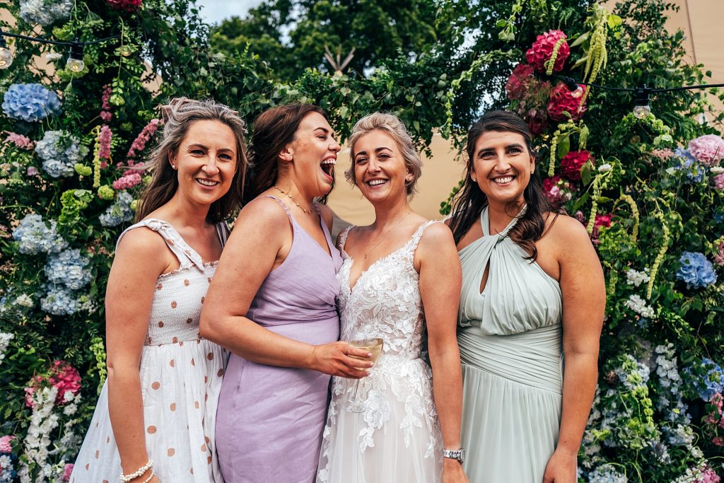 bride poses with laughing guests