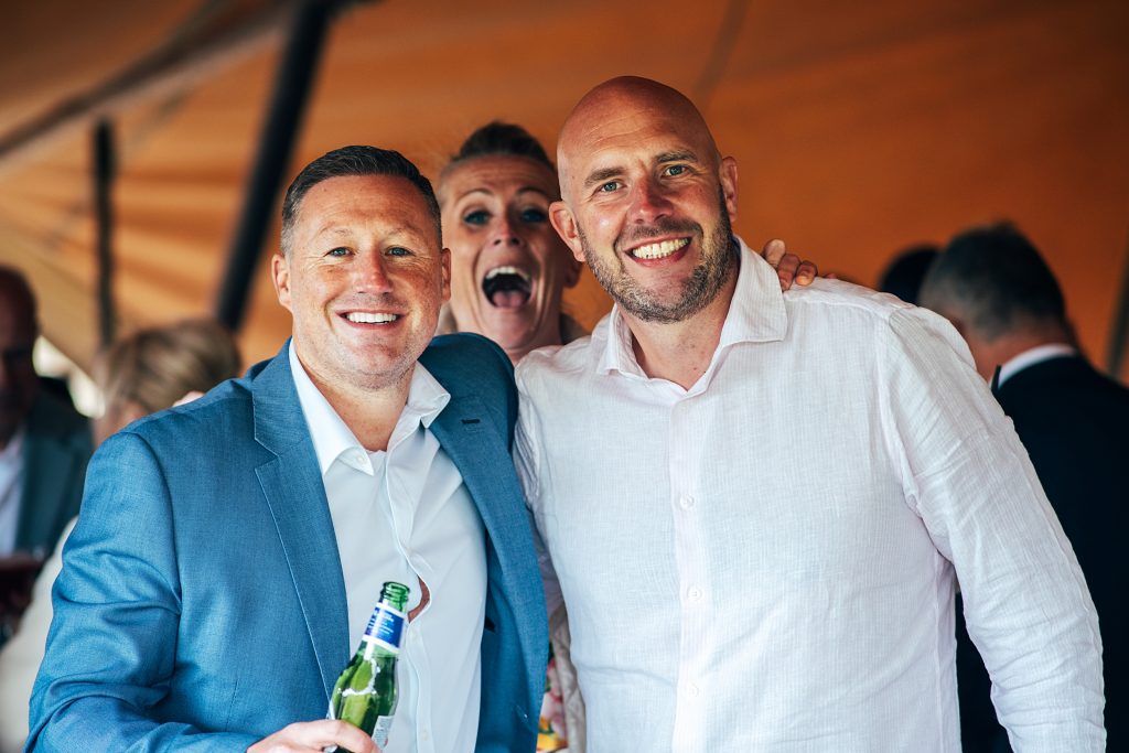 woman photo bombs two male weddings guests in a tipi