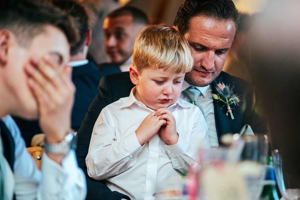 little boy looks sad on guests lap in tipi