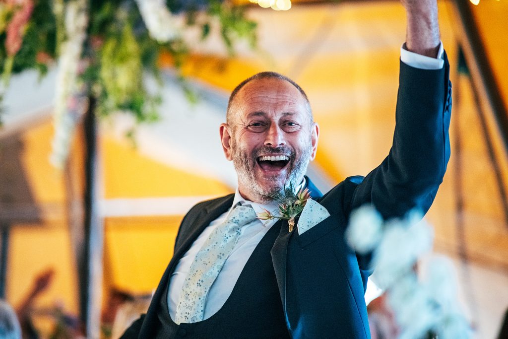 father of bride raises glass in toast in tipi