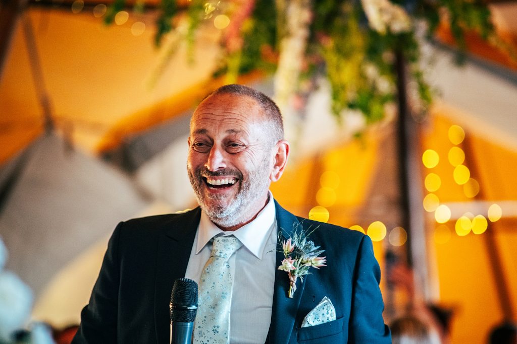 laughing father of bride gives speech in tipi