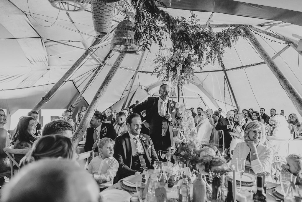 wedding guests laugh at speeches in a tipi