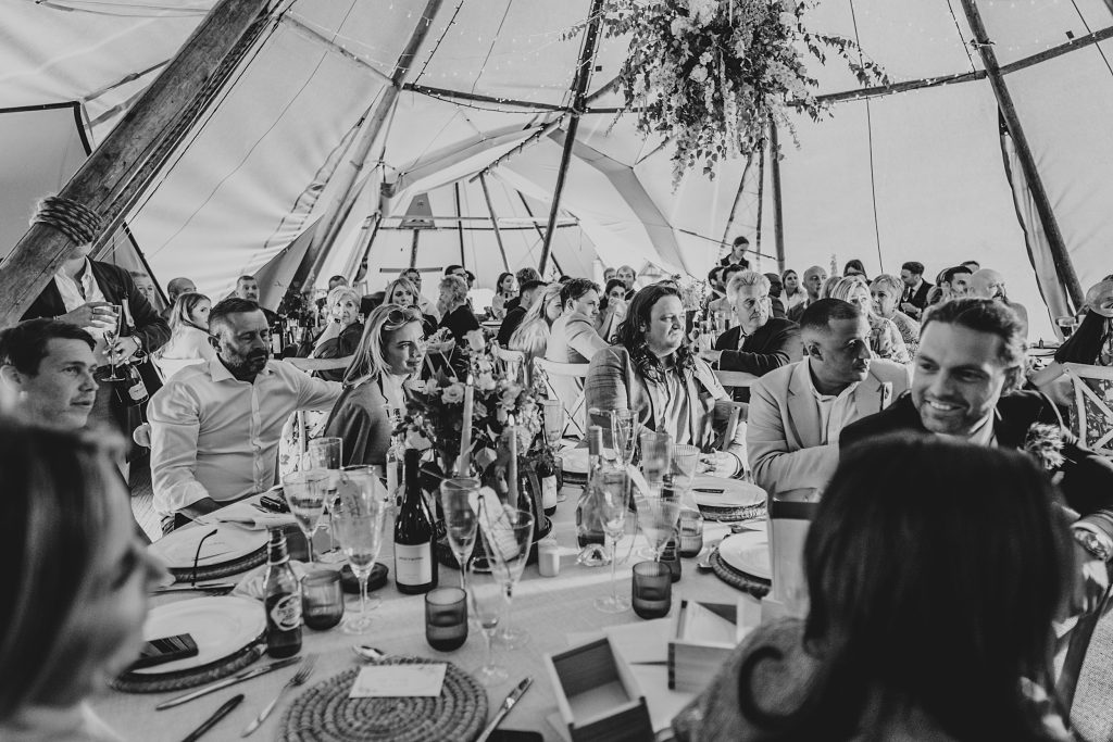 guests look emotional during wedding speech in tipi