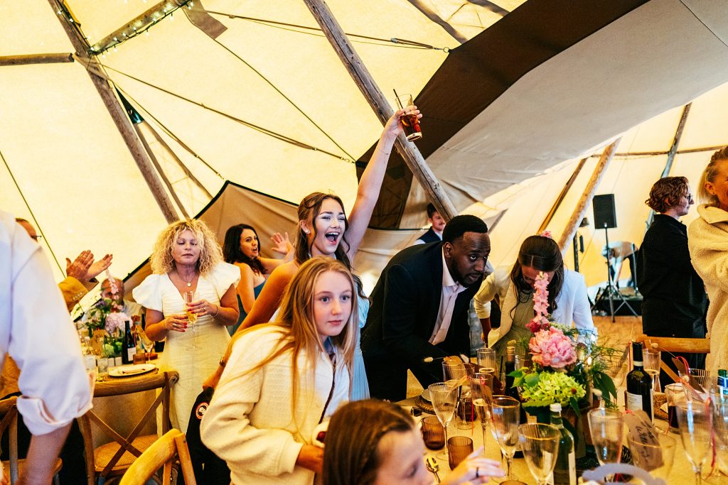 guests wave arms in air during speeches in tipi