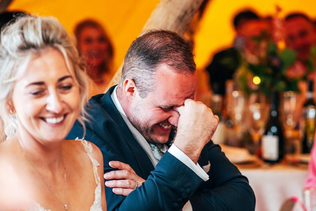 groom pinches forehead as he looks embarrassed during best mans speech