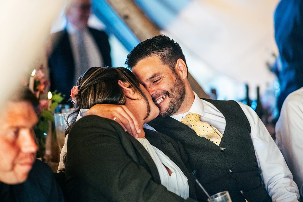 two wedding guests smile and kiss in a tipi