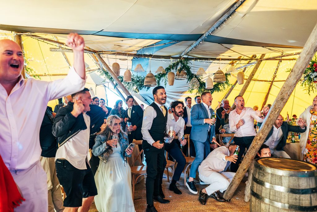 excited wedding guests watch England take penalties in a tipi