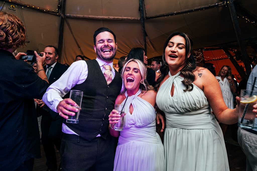 wedding guests sing on dance floor in tipi