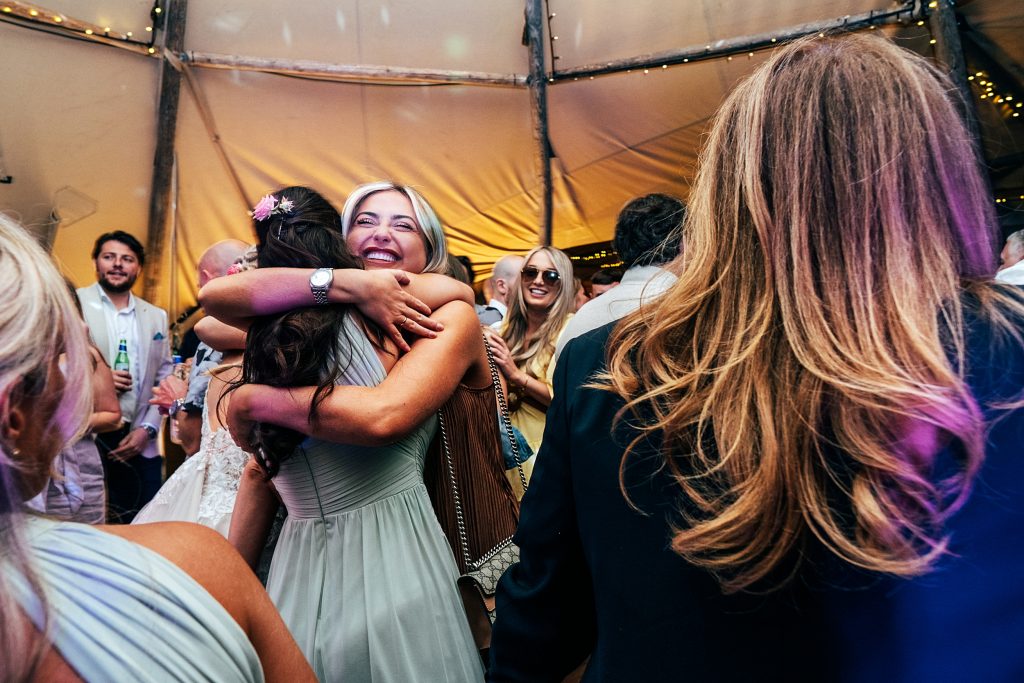 wedding guests hug on dance floor in tipi