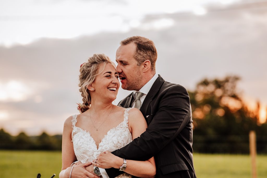 bride and groom in field at sunset