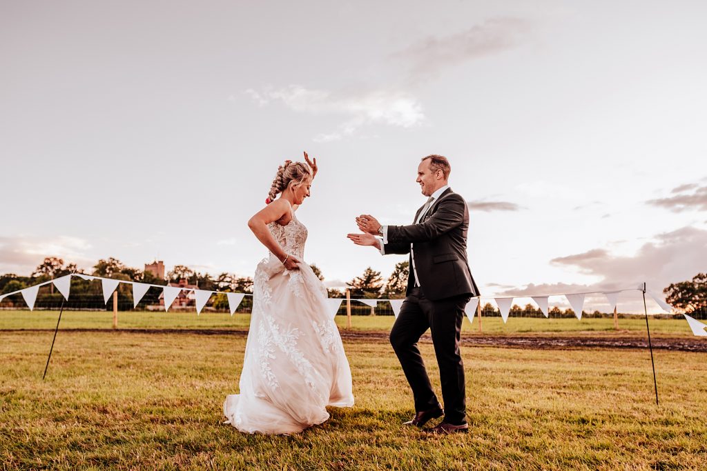 bride and groom dance in field at sunset