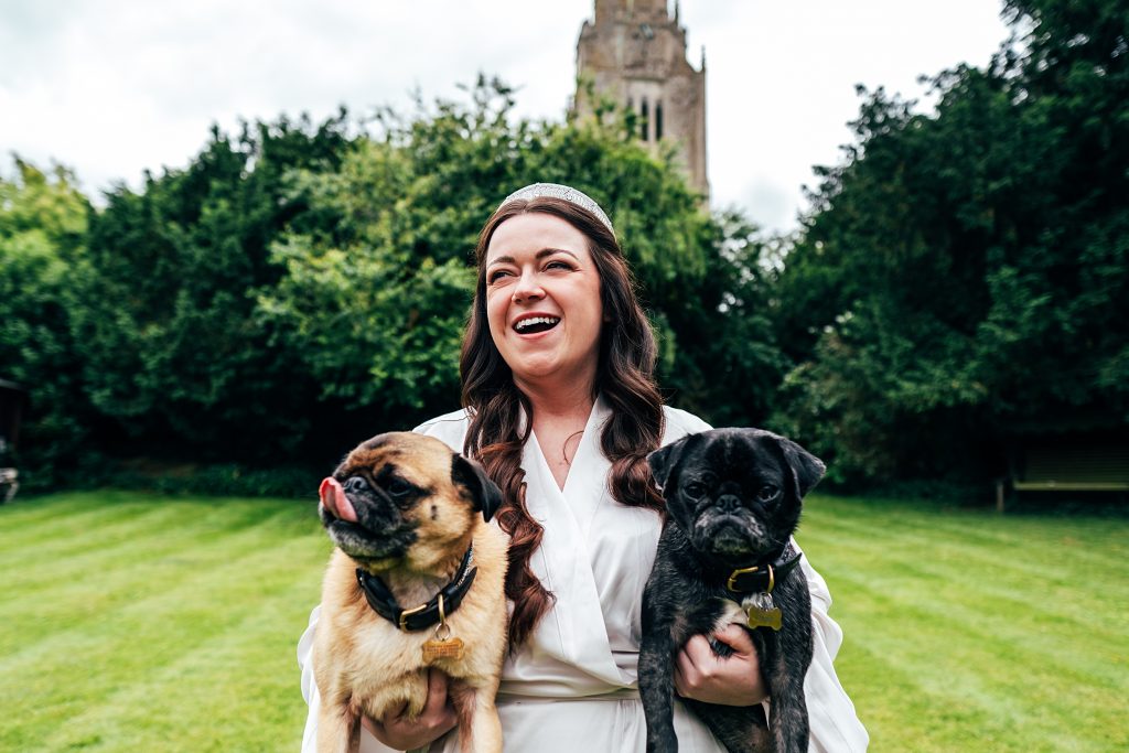 laughing bride holds two pugs back garden