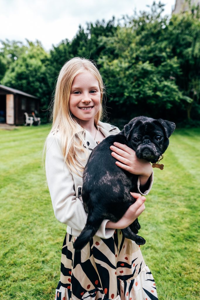 little girl hugs pug dog