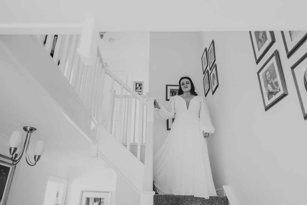 bride stands on landing of stairwell in her family home