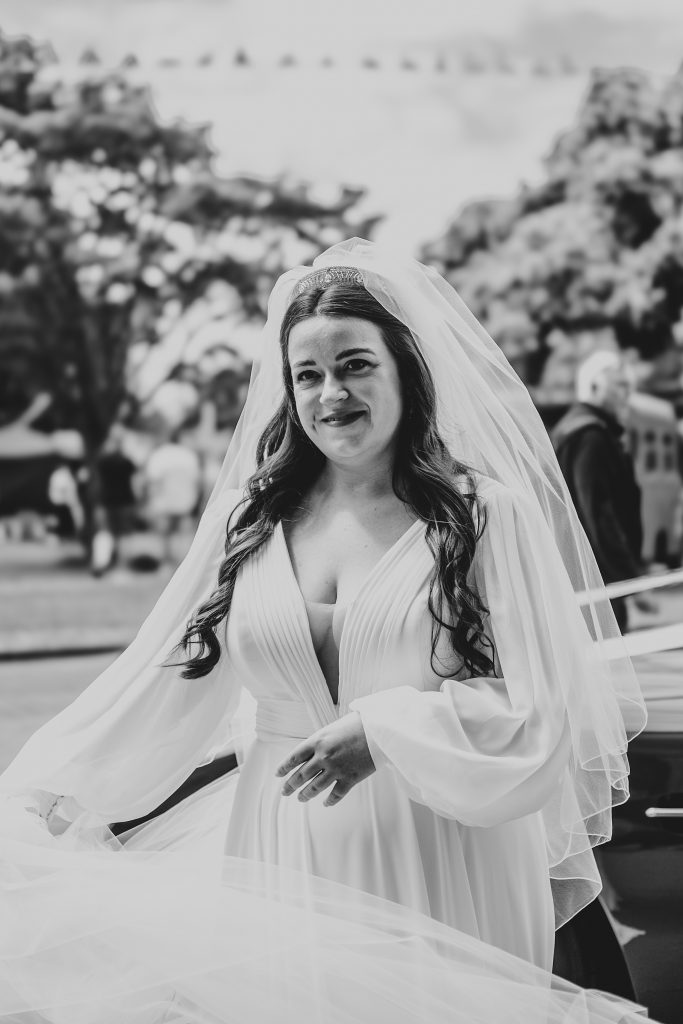 Bride adjusts veil outside Ely Cathedral