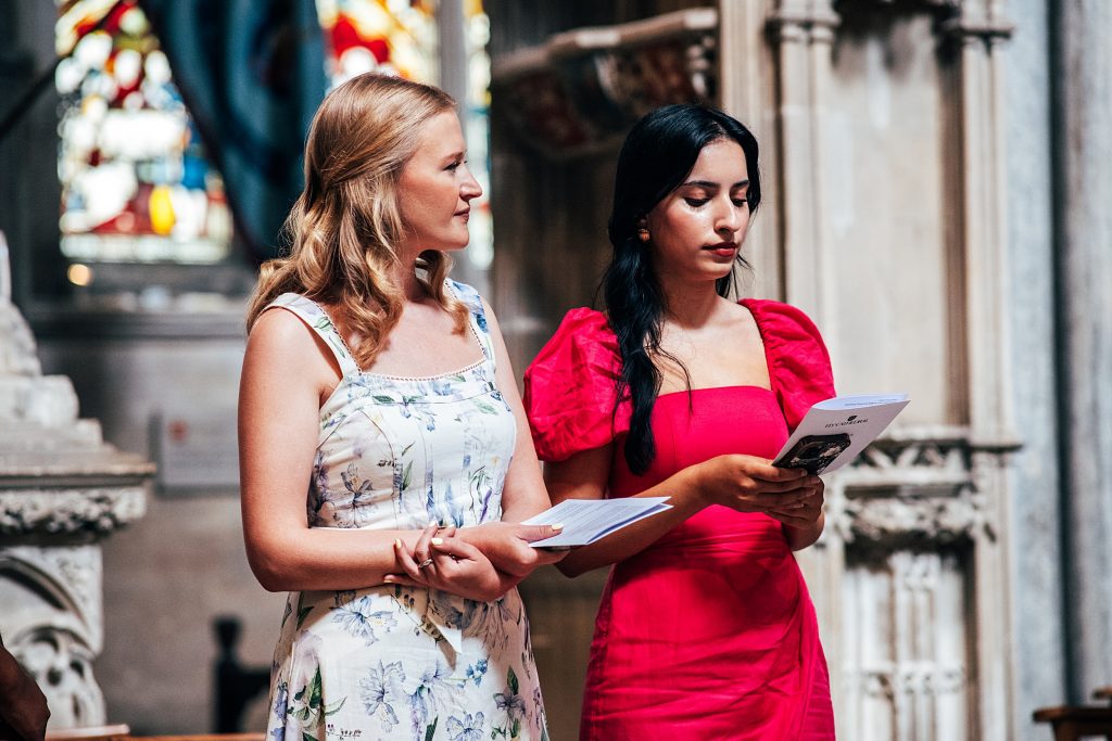 two guests hold hymn sheets at Ely Cathedral wedding