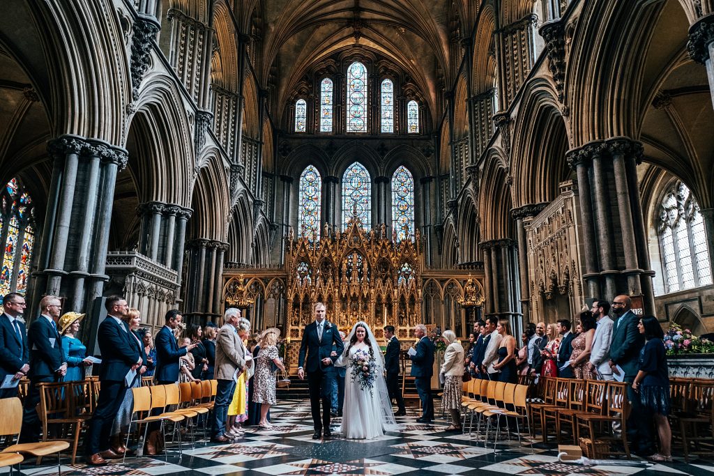 bride and groom walk up aisle at Ely cathedral